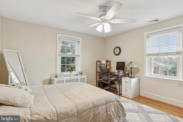 bedroom featuring radiator, hardwood / wood-style floors, and ceiling fan