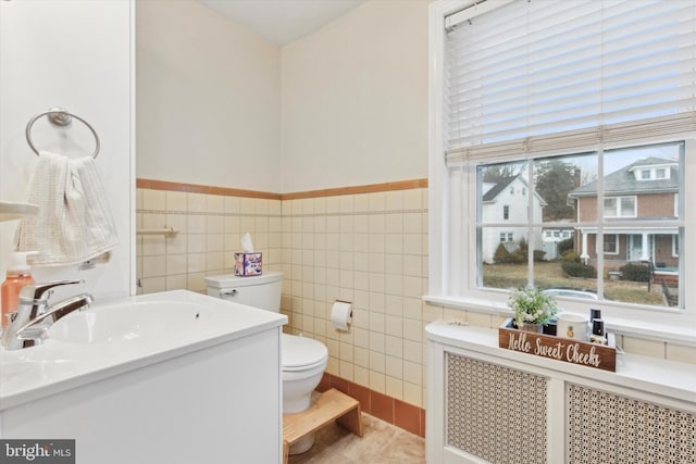 bathroom with tile patterned floors, toilet, tile walls, radiator heating unit, and vanity