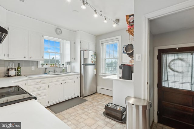 kitchen featuring sink, stainless steel fridge, white cabinets, and a baseboard radiator