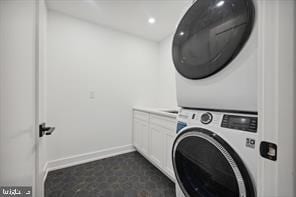 laundry room featuring cabinets and stacked washing maching and dryer