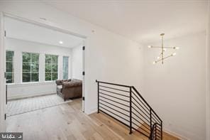 hallway with a notable chandelier and light hardwood / wood-style floors