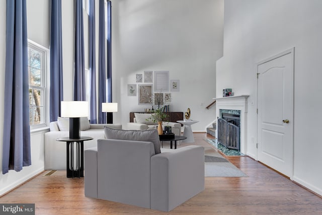 living area featuring a high ceiling, a fireplace, and wood finished floors