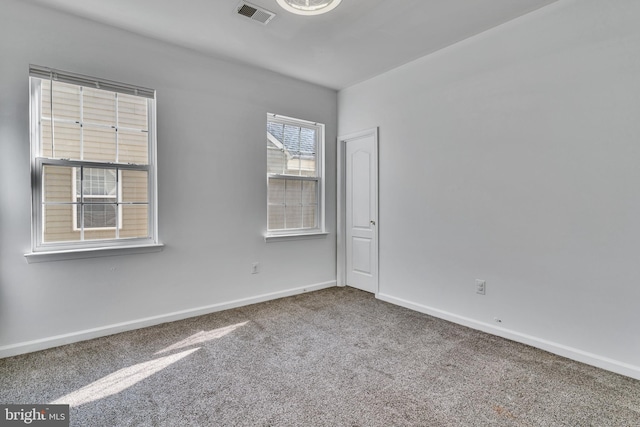 empty room featuring carpet flooring, visible vents, and baseboards