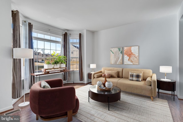 living room with baseboards, visible vents, and wood finished floors