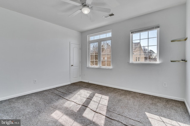 carpeted spare room with a ceiling fan, visible vents, and baseboards