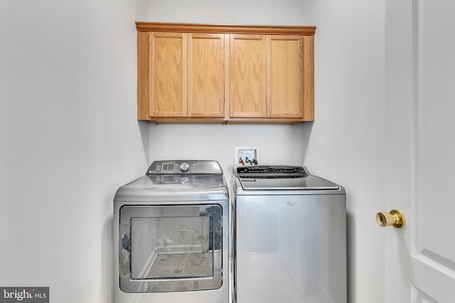 clothes washing area featuring cabinet space and washing machine and clothes dryer