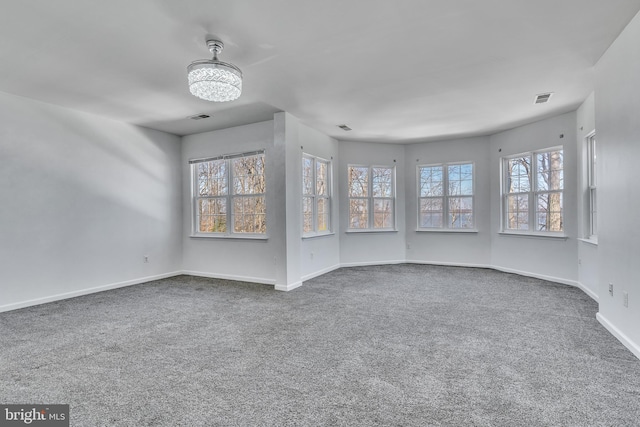 spare room featuring carpet, visible vents, and baseboards