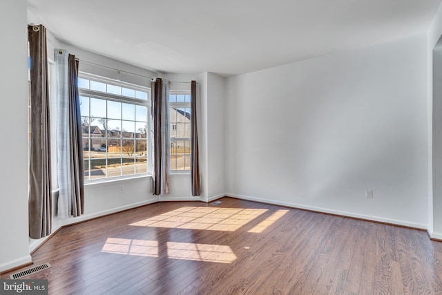 spare room featuring visible vents, baseboards, and wood finished floors