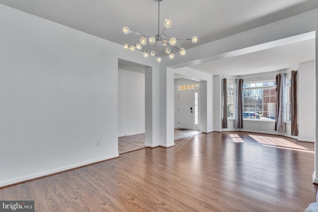 interior space featuring baseboards, wood finished floors, and a notable chandelier