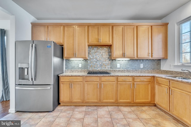 kitchen with tasteful backsplash, light stone counters, stainless steel appliances, and a sink