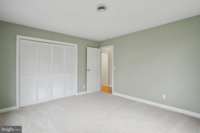 unfurnished bedroom featuring visible vents, carpet, baseboards, and a closet