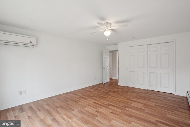 unfurnished bedroom with baseboards, light wood finished floors, and a wall mounted AC