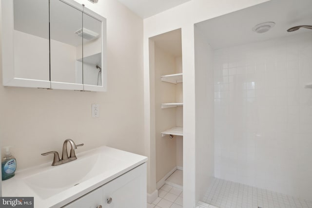 full bathroom featuring visible vents, vanity, baseboards, tiled shower, and tile patterned floors