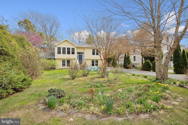 raised ranch with a front yard and stucco siding