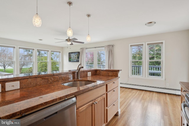kitchen featuring a sink, dishwasher, dark stone countertops, a baseboard radiator, and pendant lighting