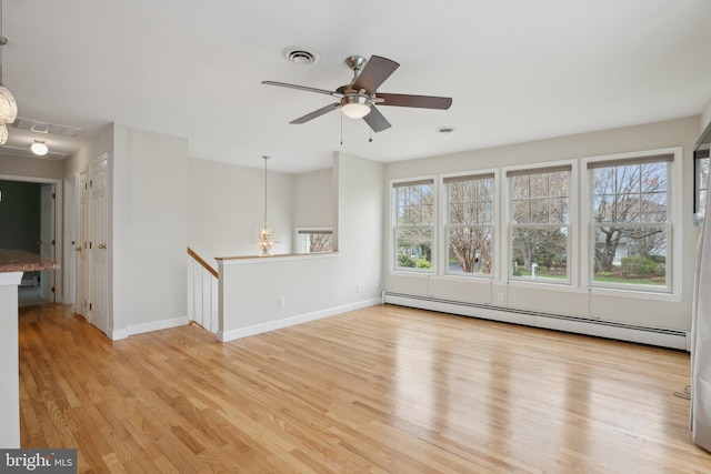 empty room featuring baseboards, baseboard heating, a ceiling fan, and light wood finished floors