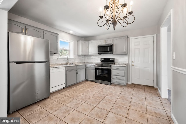 kitchen featuring tasteful backsplash, decorative light fixtures, light tile patterned floors, appliances with stainless steel finishes, and gray cabinets