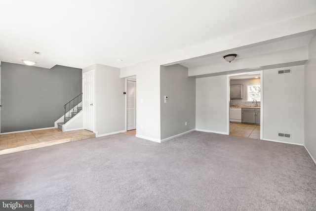 unfurnished living room featuring sink and light carpet