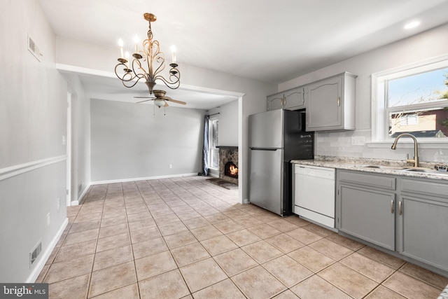 kitchen featuring gray cabinets, stainless steel refrigerator, tasteful backsplash, dishwasher, and sink