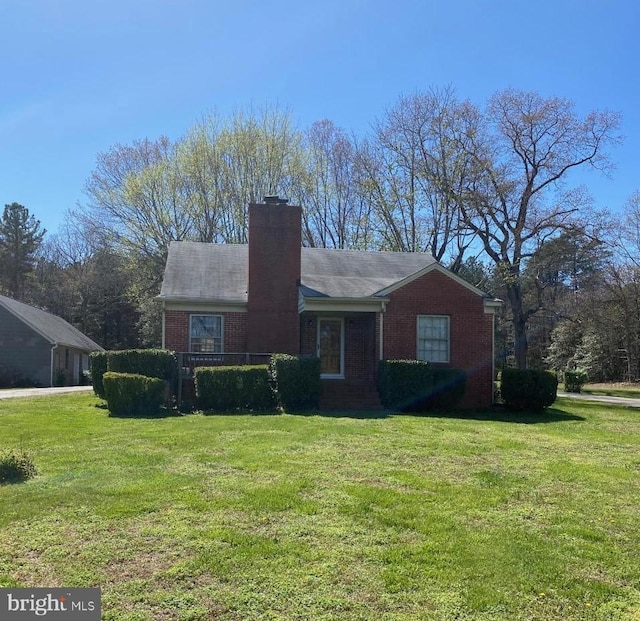 view of front facade with a chimney, a front lawn, and brick siding