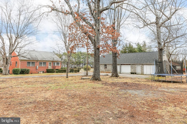 view of front of property with a garage, a trampoline, a chimney, and brick siding