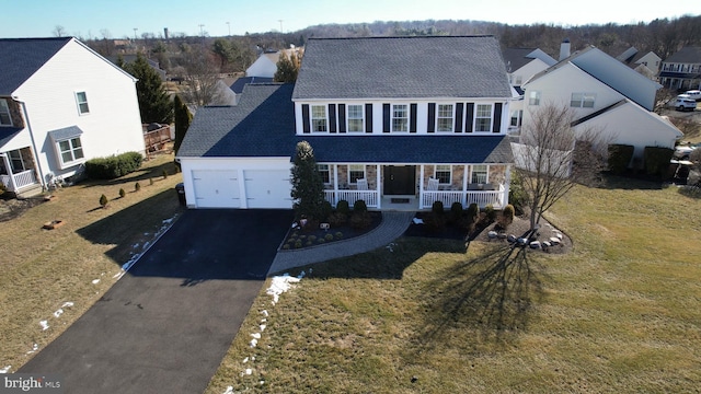 view of front facade featuring a garage, covered porch, and a front lawn