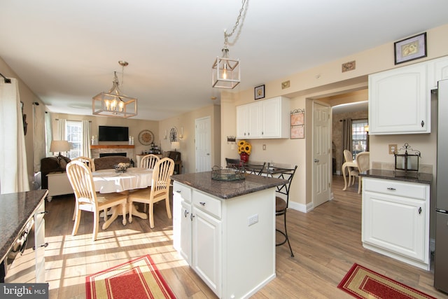 kitchen with white cabinetry, a center island, light hardwood / wood-style floors, and hanging light fixtures