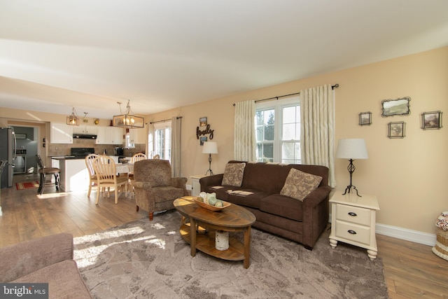 living room with plenty of natural light, dark wood-type flooring, and a notable chandelier