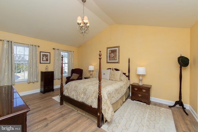 bedroom with hardwood / wood-style flooring, vaulted ceiling, and an inviting chandelier