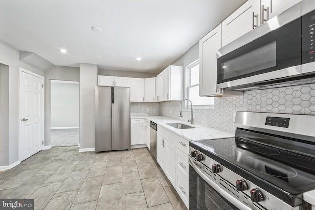 kitchen featuring sink, white cabinetry, backsplash, stainless steel appliances, and light stone countertops