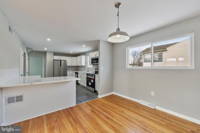 kitchen featuring appliances with stainless steel finishes, sink, white cabinets, decorative backsplash, and kitchen peninsula