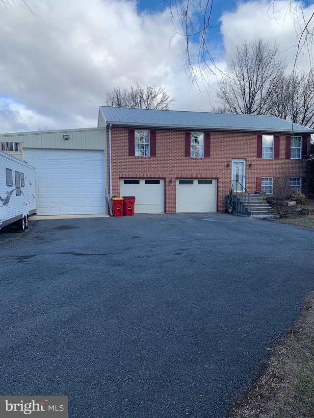 bi-level home with a garage, driveway, and brick siding