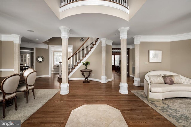 entrance foyer with ornate columns, stairs, ornamental molding, and dark wood-style floors