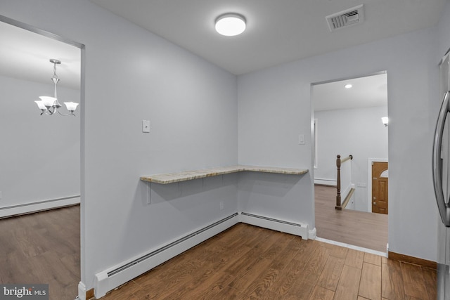 interior space with baseboard heating, wood-type flooring, and a notable chandelier