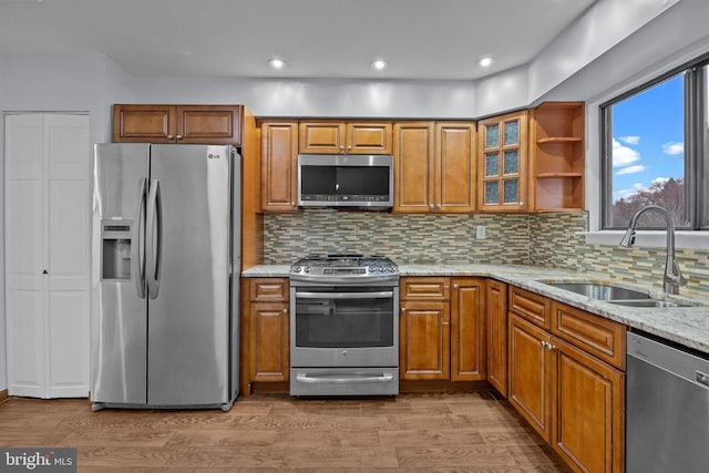 kitchen featuring appliances with stainless steel finishes, hardwood / wood-style floors, tasteful backsplash, sink, and light stone counters