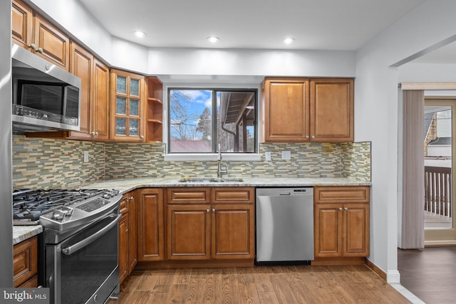 kitchen featuring light stone counters, appliances with stainless steel finishes, light hardwood / wood-style floors, and sink