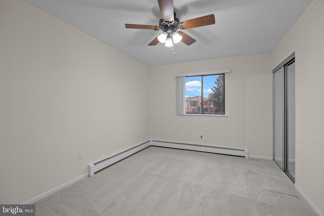 unfurnished bedroom with a baseboard heating unit, light colored carpet, ceiling fan, and a closet