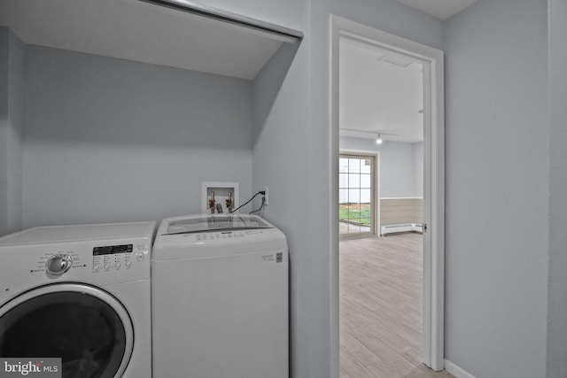 clothes washing area featuring rail lighting, washing machine and dryer, and light wood-type flooring