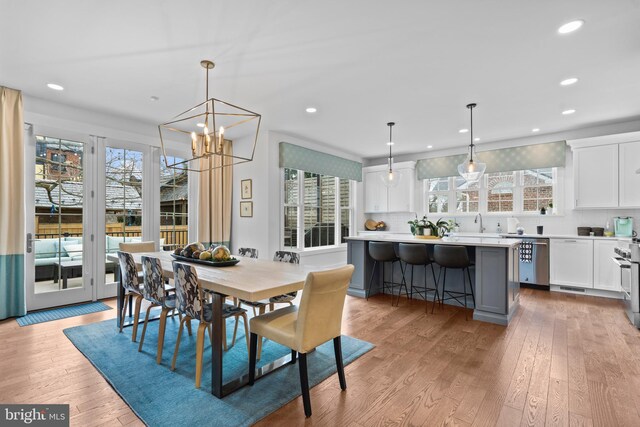 dining area with light wood-style floors, recessed lighting, and a chandelier