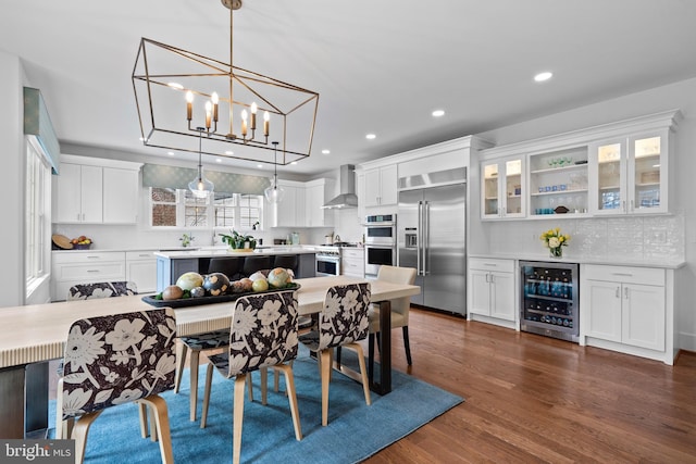 dining area with beverage cooler, a chandelier, dark wood finished floors, and recessed lighting