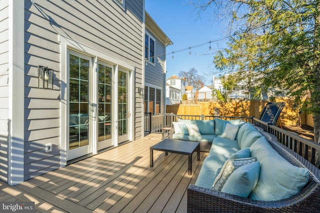 wooden deck with an outdoor hangout area and fence