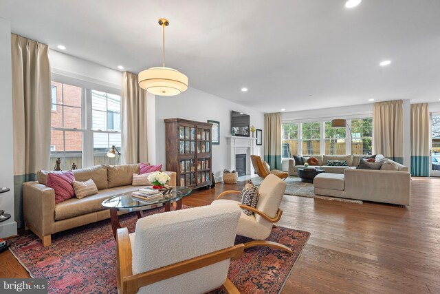 living area featuring a glass covered fireplace, recessed lighting, and wood finished floors