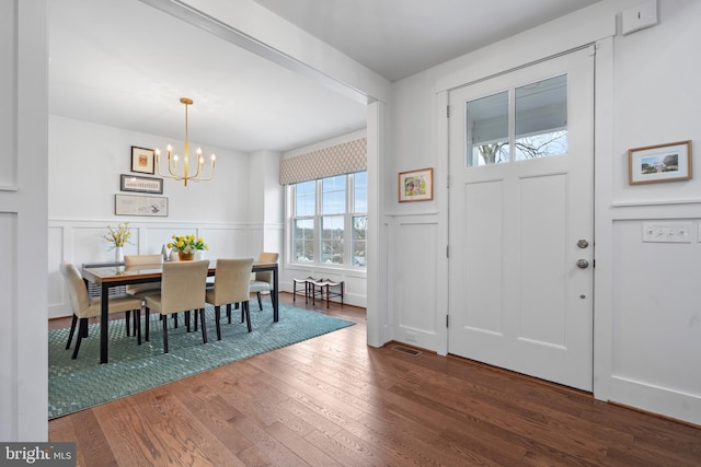 entryway with a chandelier, a wainscoted wall, a decorative wall, and hardwood / wood-style flooring