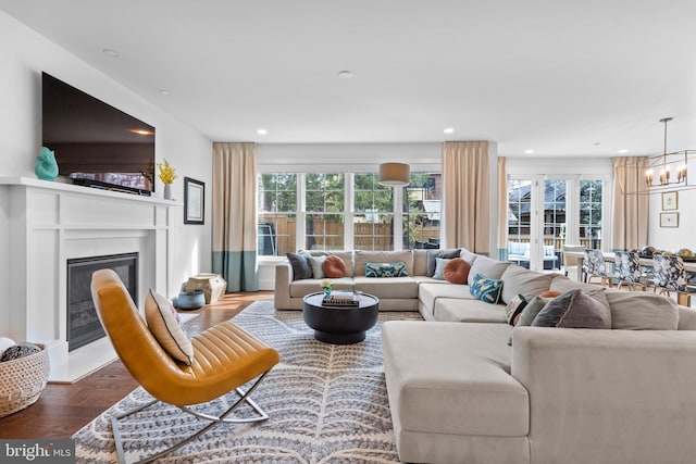 living area featuring a chandelier, a glass covered fireplace, dark wood finished floors, and recessed lighting