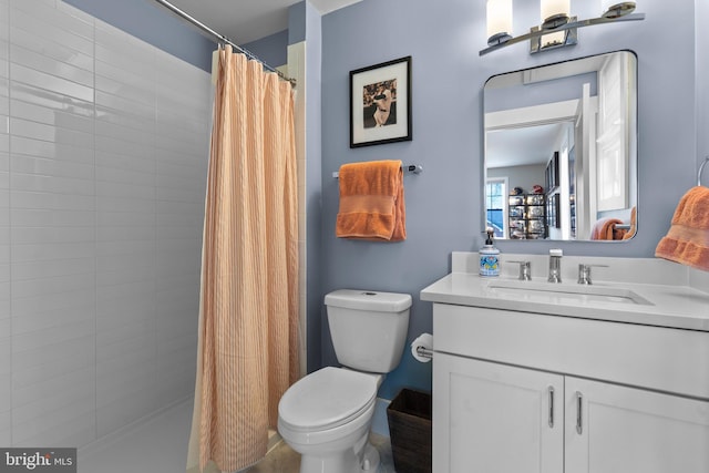 bathroom with a tile shower, vanity, and toilet