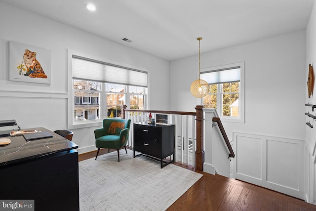 interior space with visible vents, dark wood-style floors, a wainscoted wall, an upstairs landing, and a decorative wall