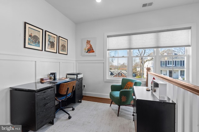 office with plenty of natural light, visible vents, a decorative wall, and wood finished floors