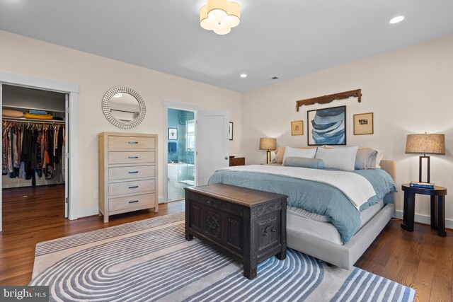 bedroom with a spacious closet, baseboards, dark wood-style flooring, and recessed lighting