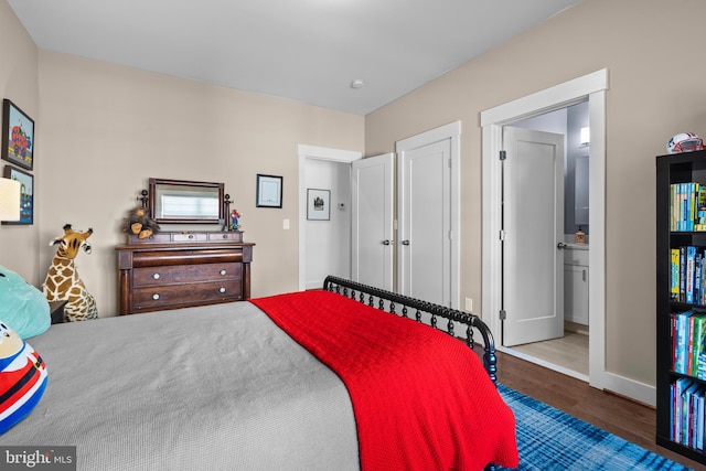 bedroom featuring baseboards, ensuite bath, and wood finished floors