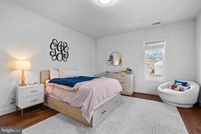 bedroom featuring visible vents, baseboards, and wood finished floors